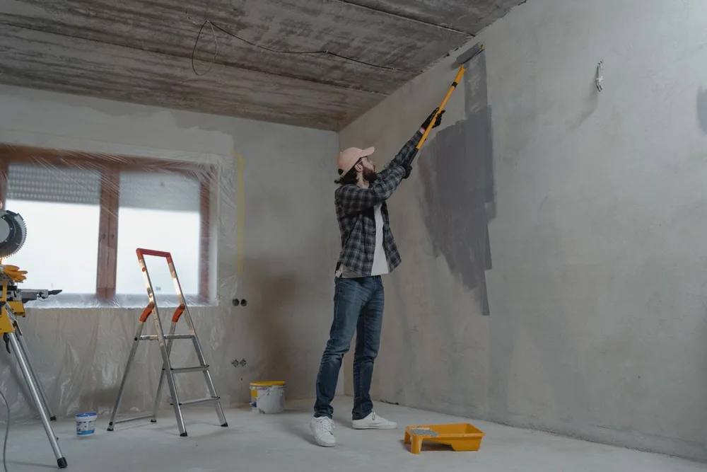 Decorator painting an interior wall with a roller